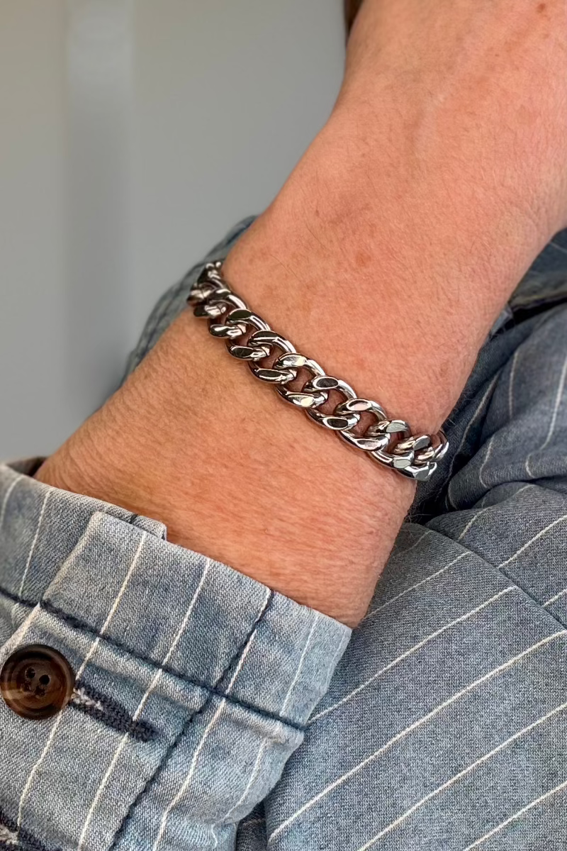 Silver cuban chain bracelet worn on a woman's wrist.