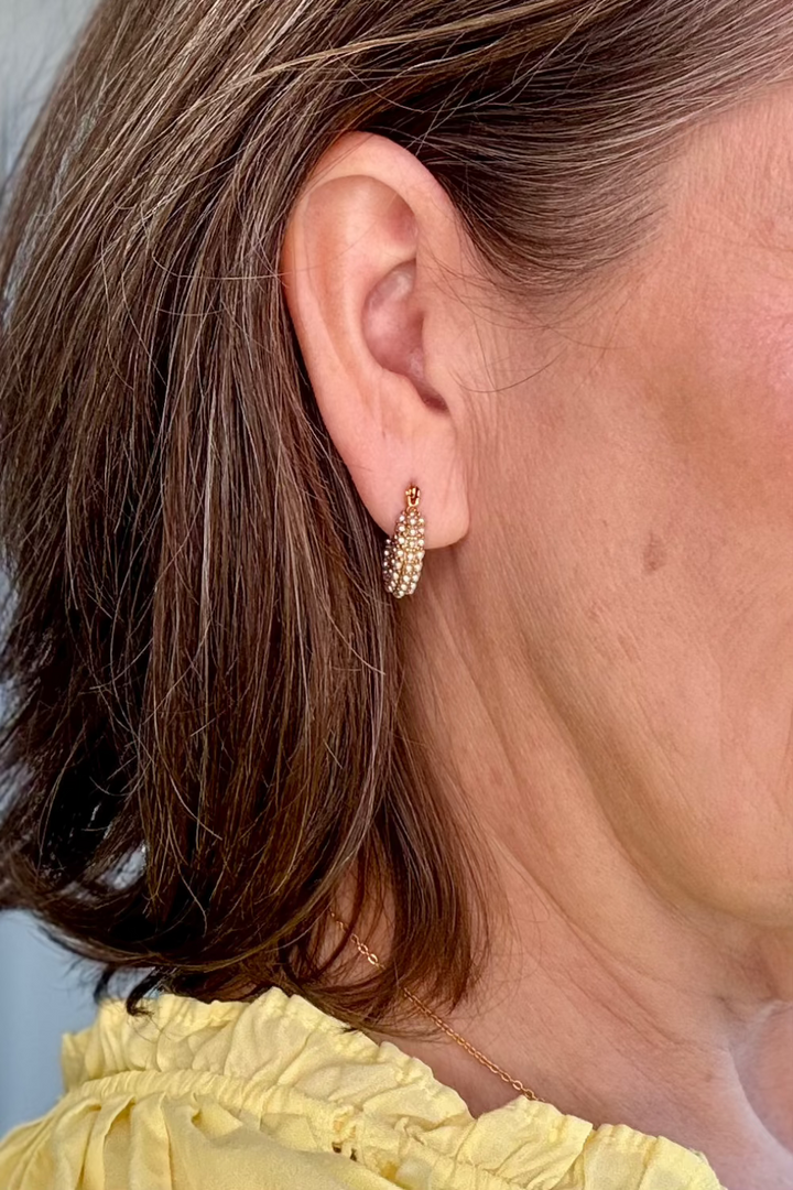 Close up of a woman's pearl and gold earring.