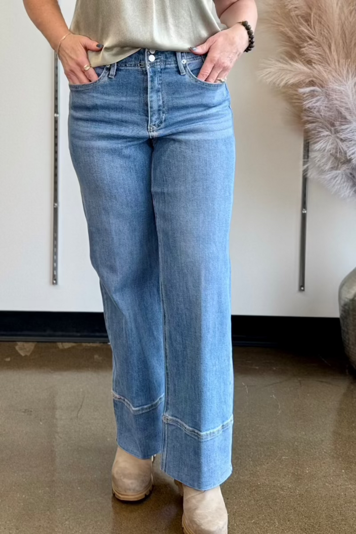 Close up of woman wearing medium wash jeans with a wide cuff.