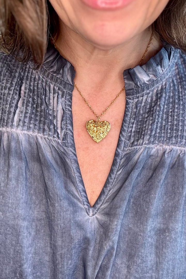 Close up of woman wearing a gold heart locket.